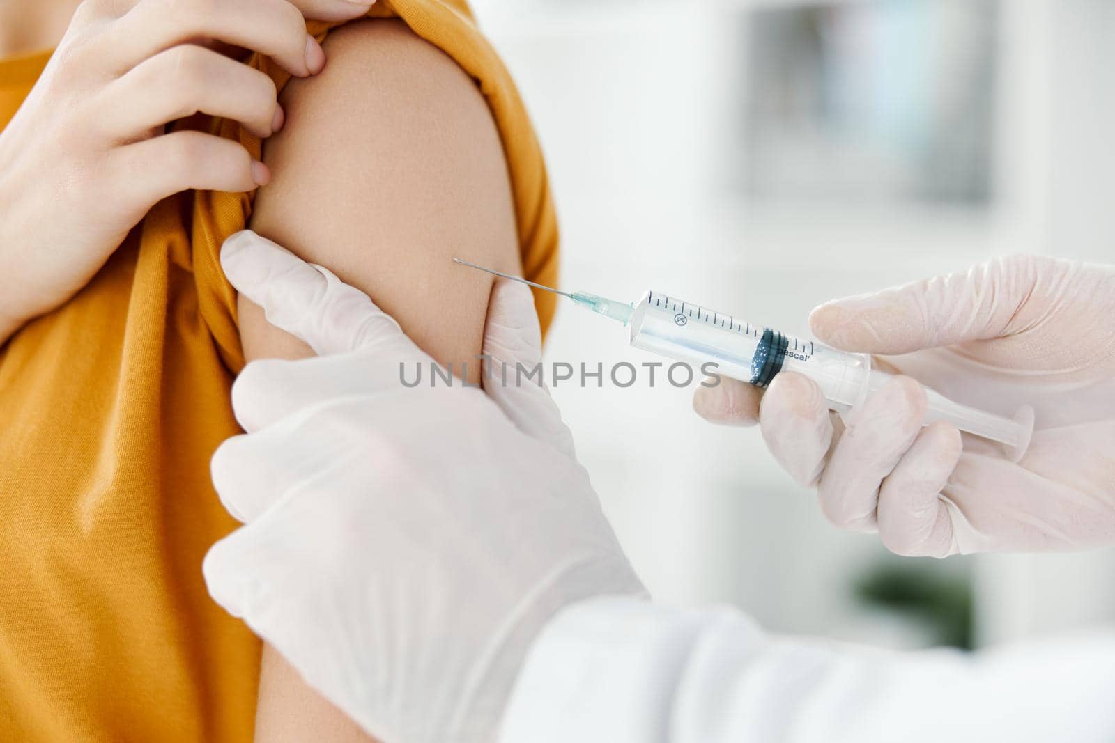 doctor injects a vaccine into the shoulder of a female patient in a medical mask in a hospital side view. High quality photo