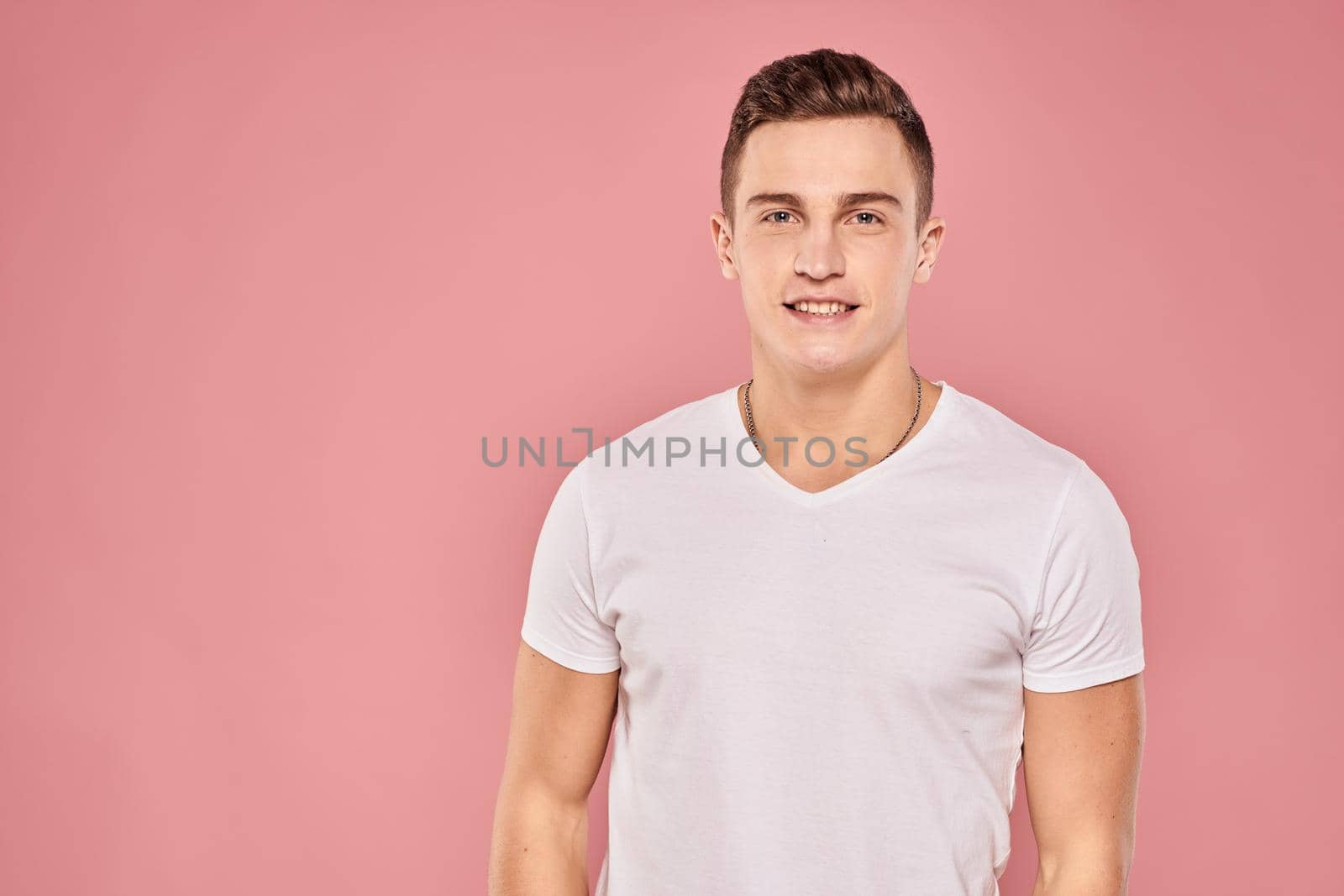 Emotional man gesturing with his hands white t-shirt pink isolated background. High quality photo