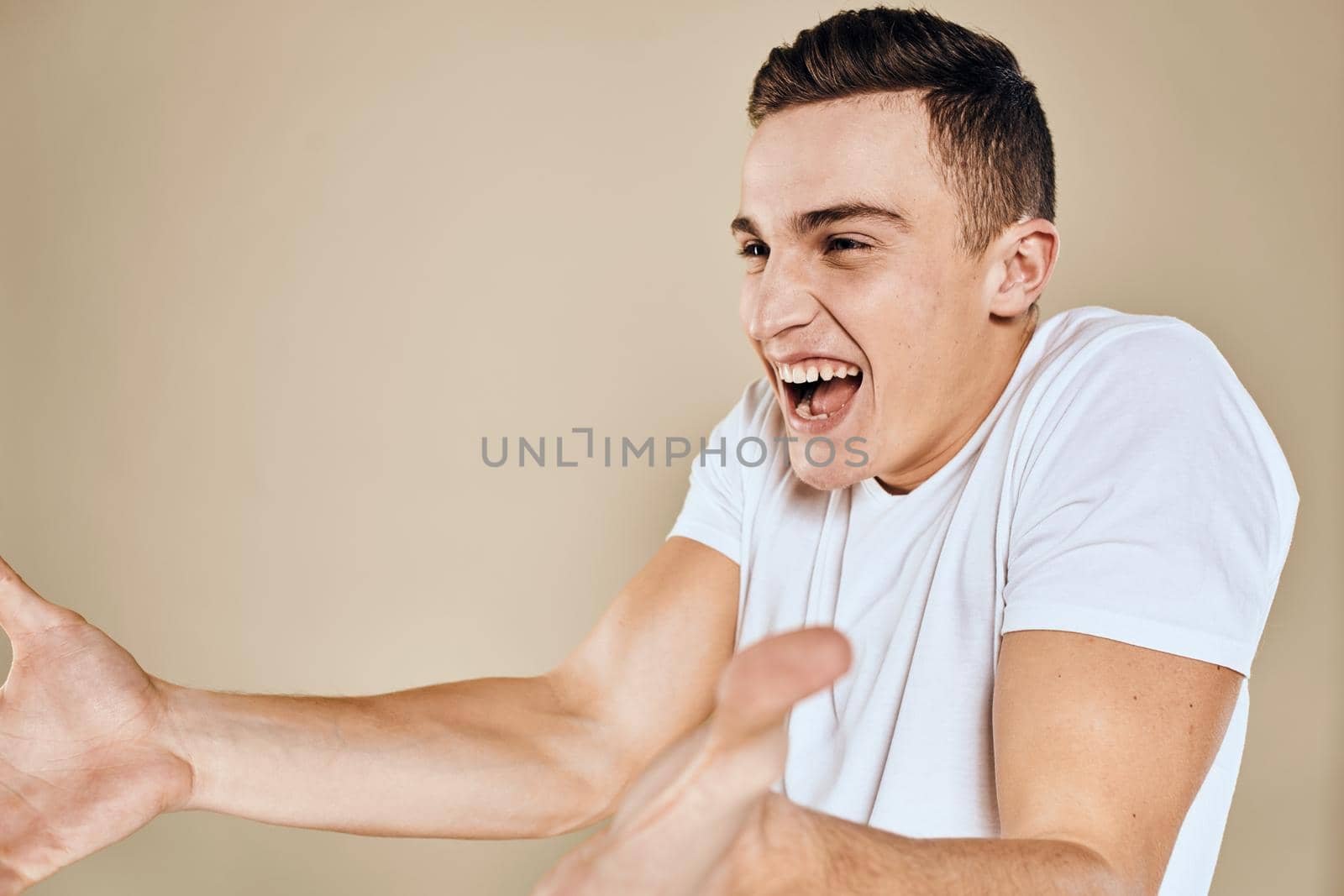 Emotional man white t-shirt gestures with hands lifestyle beige background by SHOTPRIME