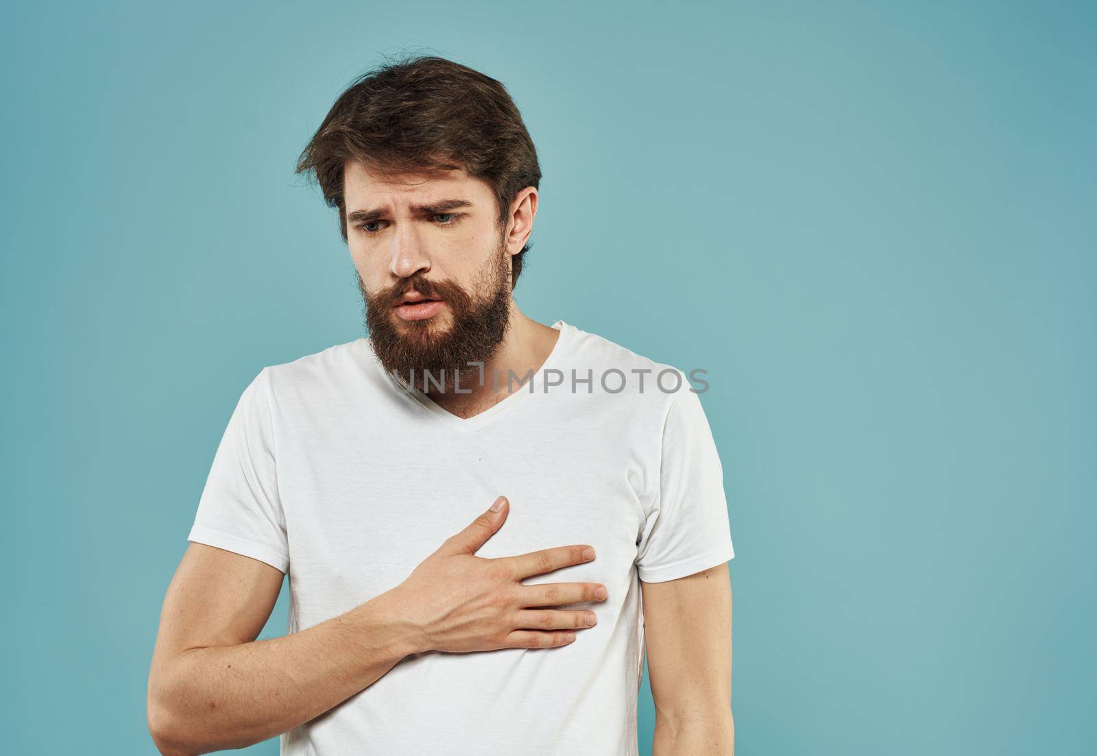 Guy in a white t-shirt on a blue background sad face and cropped view of the model. High quality photo