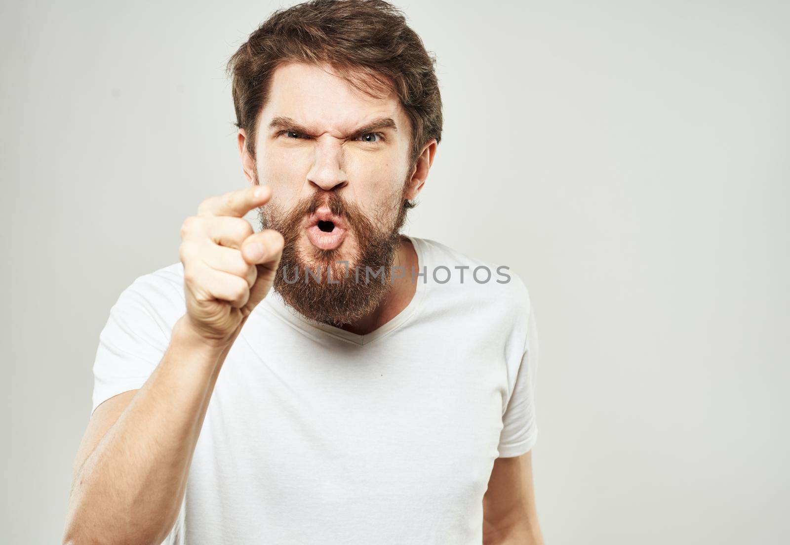 Aggressive man gestures with his hands on a light background stress emotions irritability by SHOTPRIME