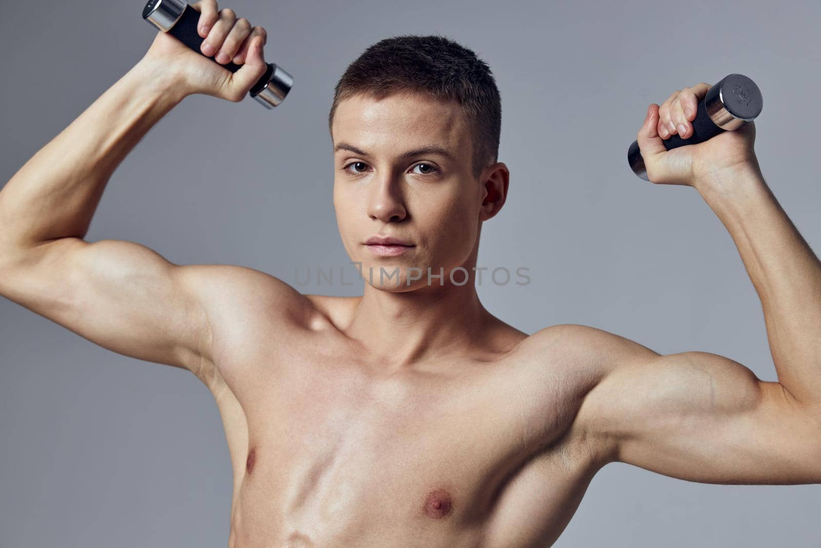 handsome man with a pumped-up body dumbbells in his hands workout muscles. High quality photo