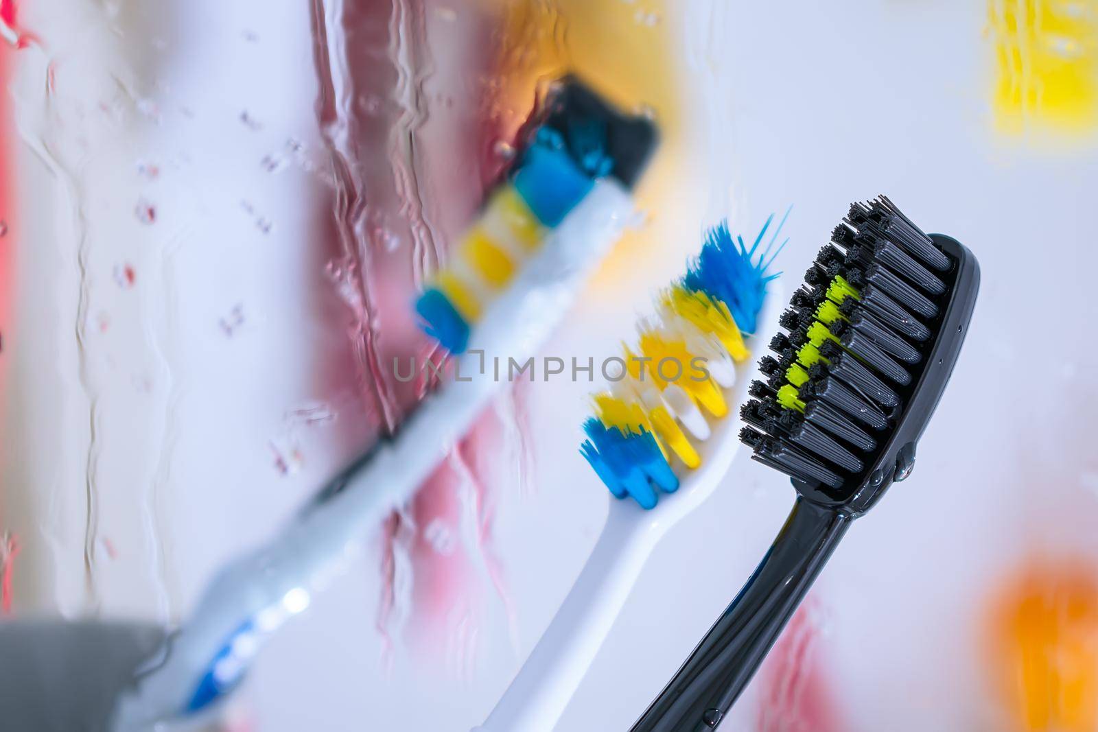 Black toothbrush in the bathroom for cleaning teeth and personal hygiene on the background of a wet mirror by Skaron