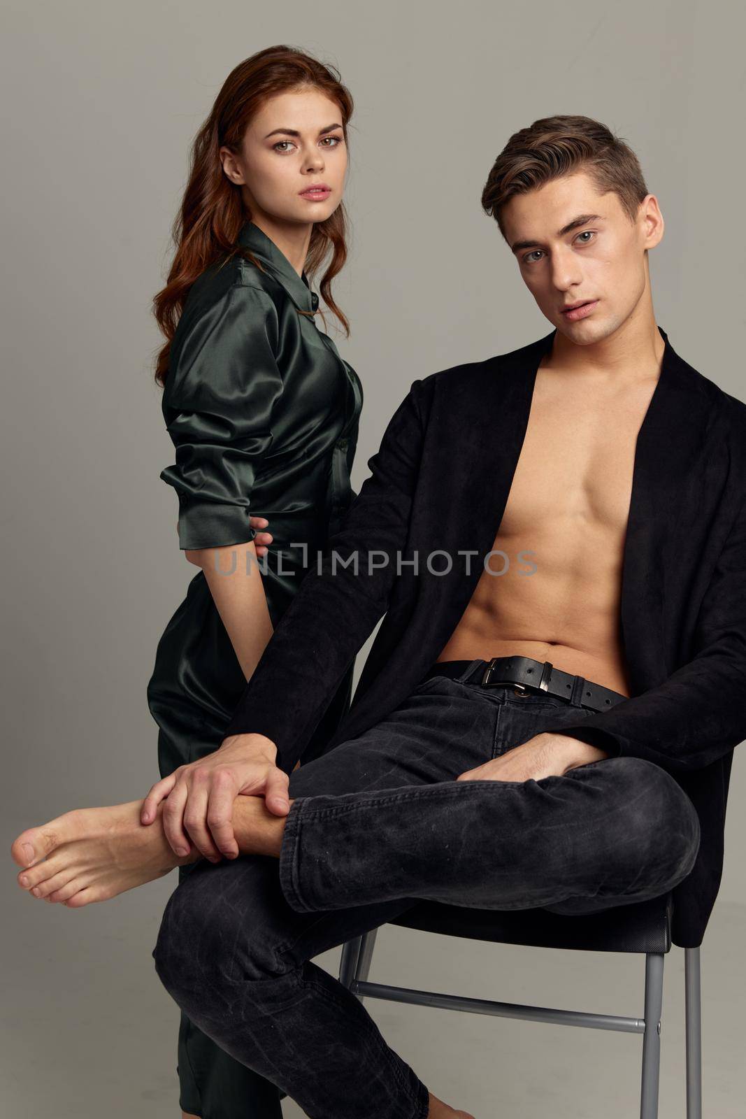 A man with an unbuttoned shirt sits on a chair next to a woman romance luxury seduction. High quality photo