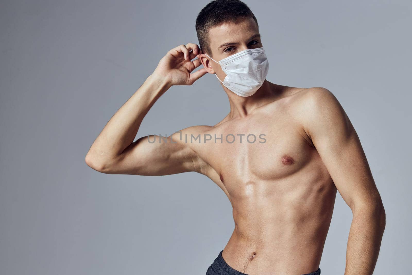 a man in a medical mask with a pumped up press holds his hand near his head posing health protection. High quality photo