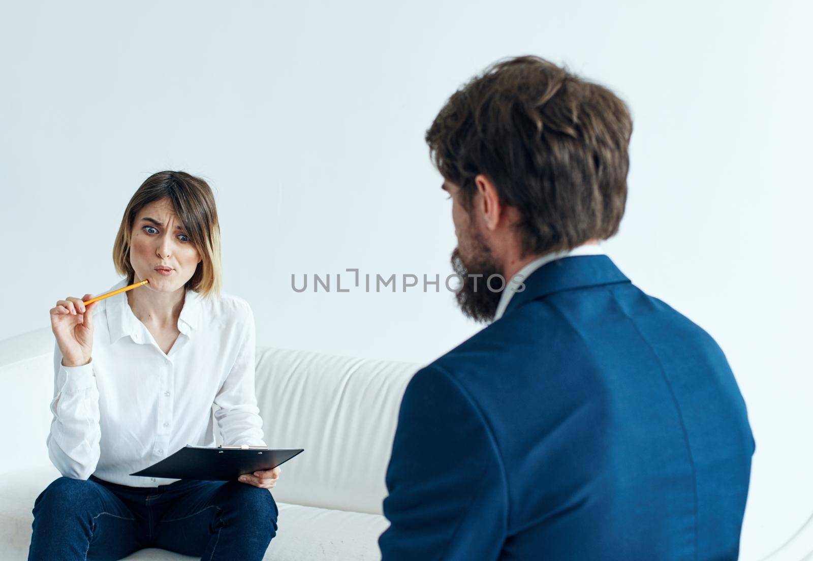 Business man in a classic suit and a woman on the couch with documents in the hands of a psychologist . High quality photo