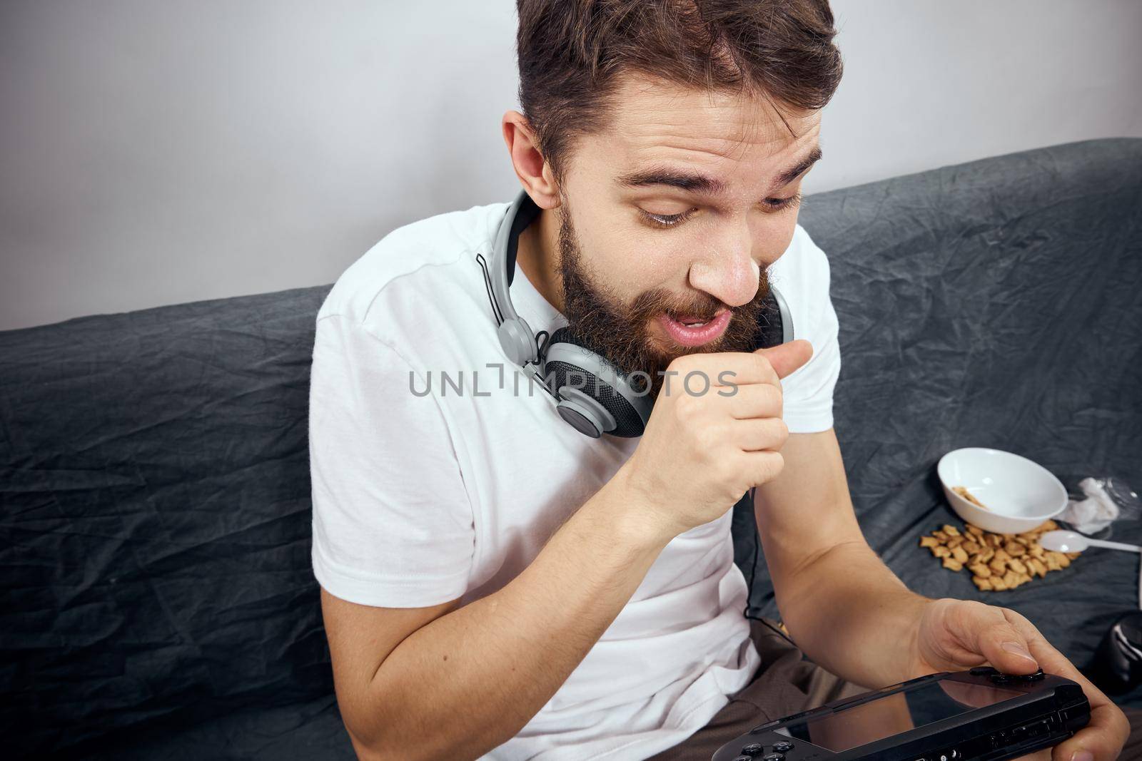 cheerful man sitting on the couch playing entertainment technology by SHOTPRIME