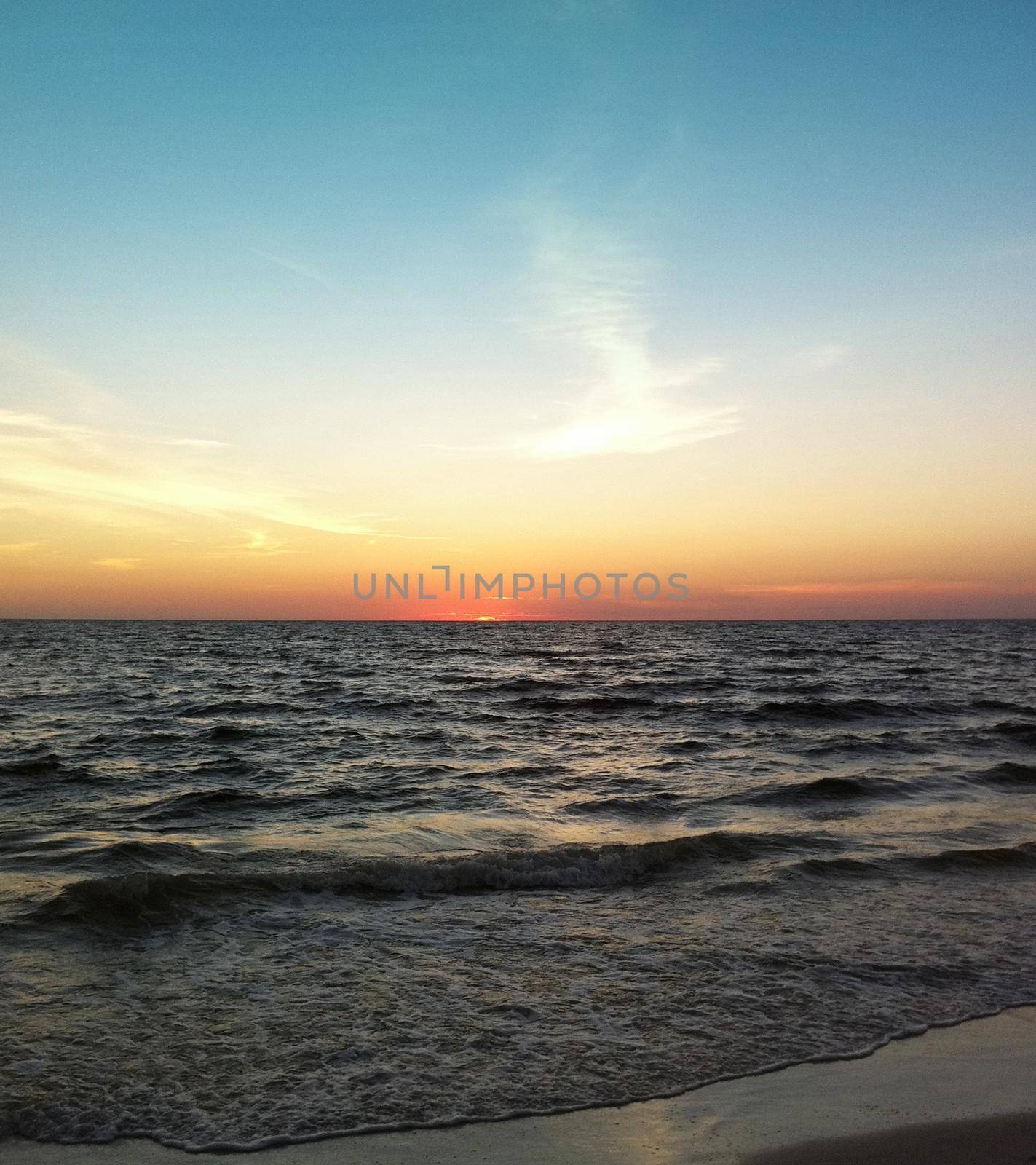 Sunset at the beach The sky is blue and orange.