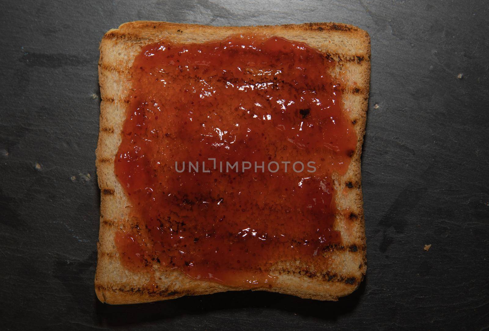 Toasted sliced bread with strawberry jam and black background