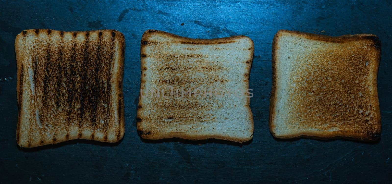 Three slices of toasted bread on a black background by xavier_photo