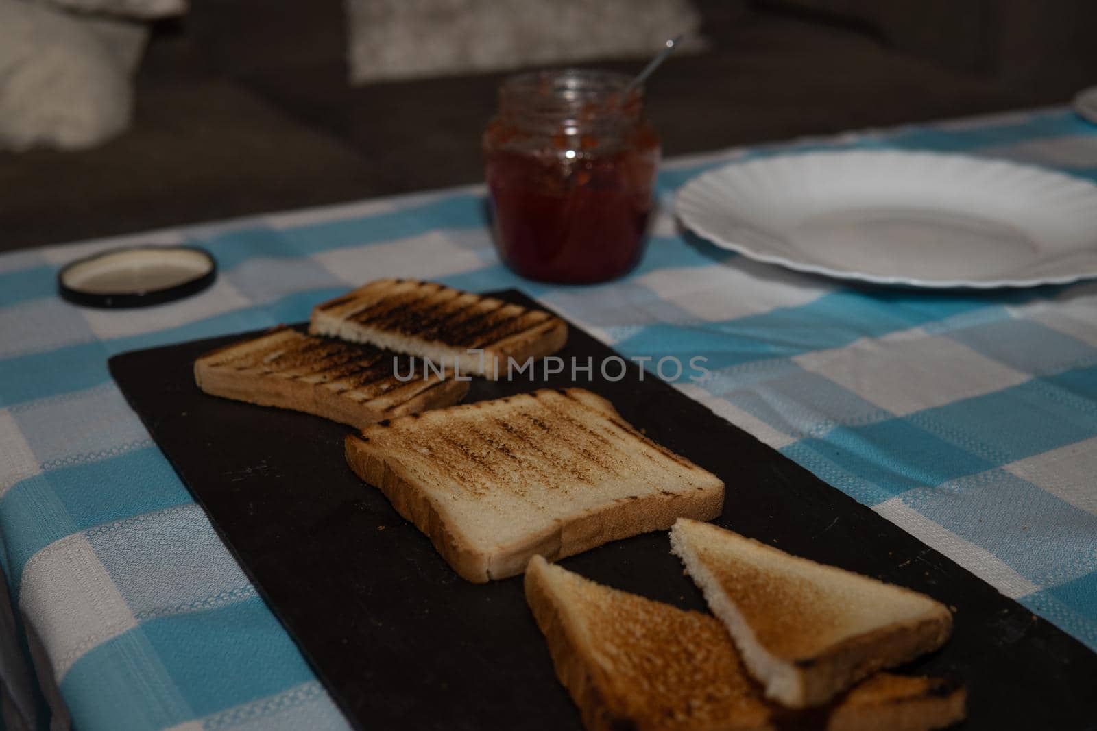 Toasted bread board with jams and a pretty blue and white tablecloth