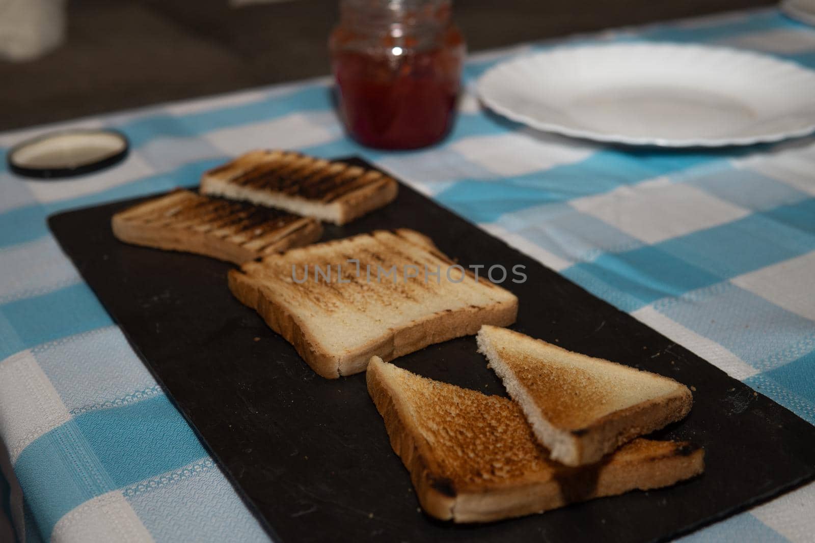 Toasted bread board with jams and a pretty blue and white tablecloth