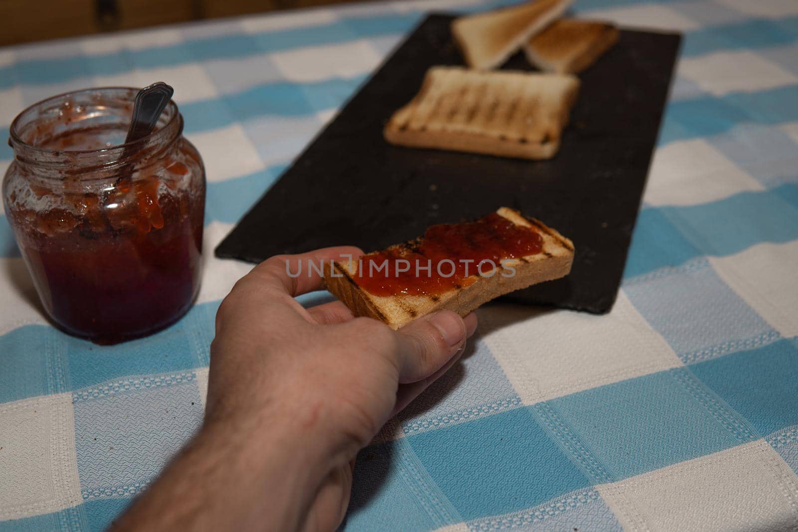 Hand clutching a piece of toast with jam