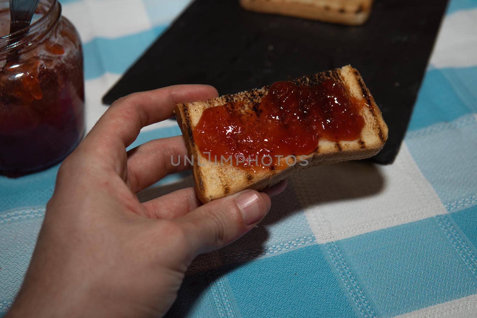 Hand clutching a piece of toast with jam