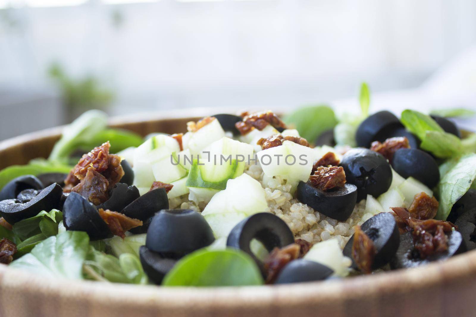 Quinoa, lettuce, lambs lettuce, black olives and cucumber salad. No people