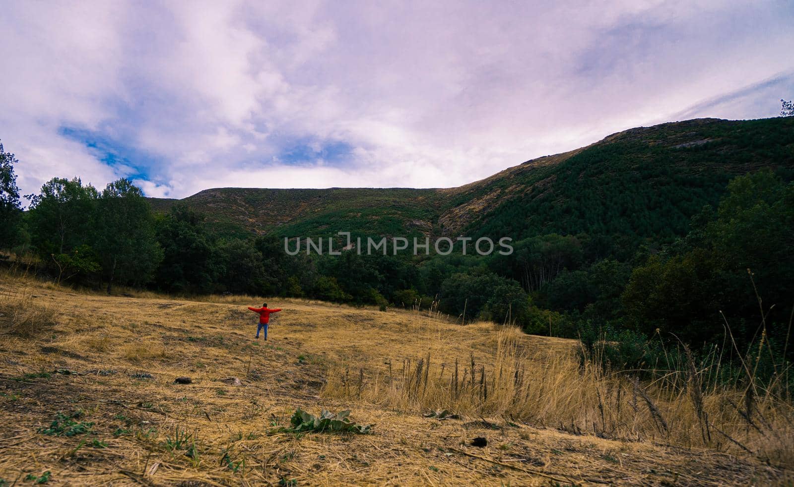 Dry meadow surrounded by mountains and a person in the background