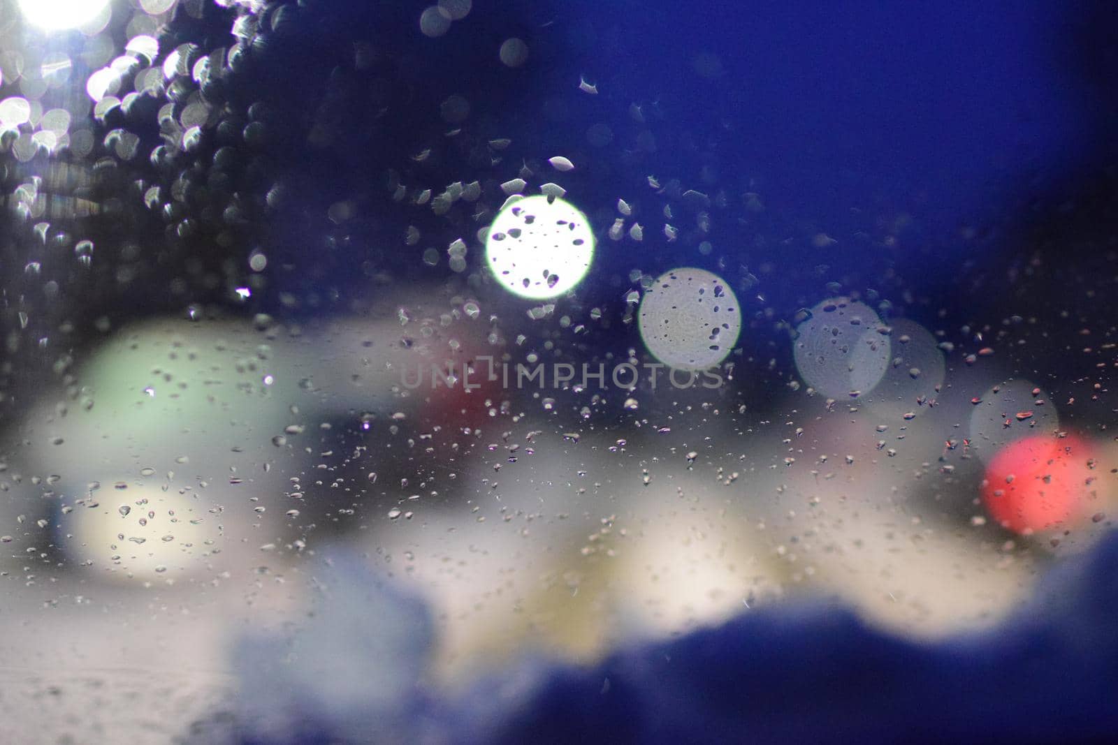 View through windshield on wintry road with snow on the hood against a blurred background at night