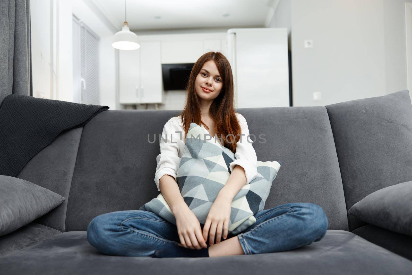 woman sitting on a sofa with a pillow in her hands at home in an apartment. High quality photo