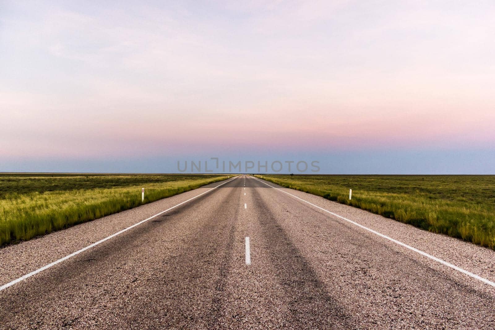 panorama of a straight road through the outback of Australia, after a beautiful sunset
