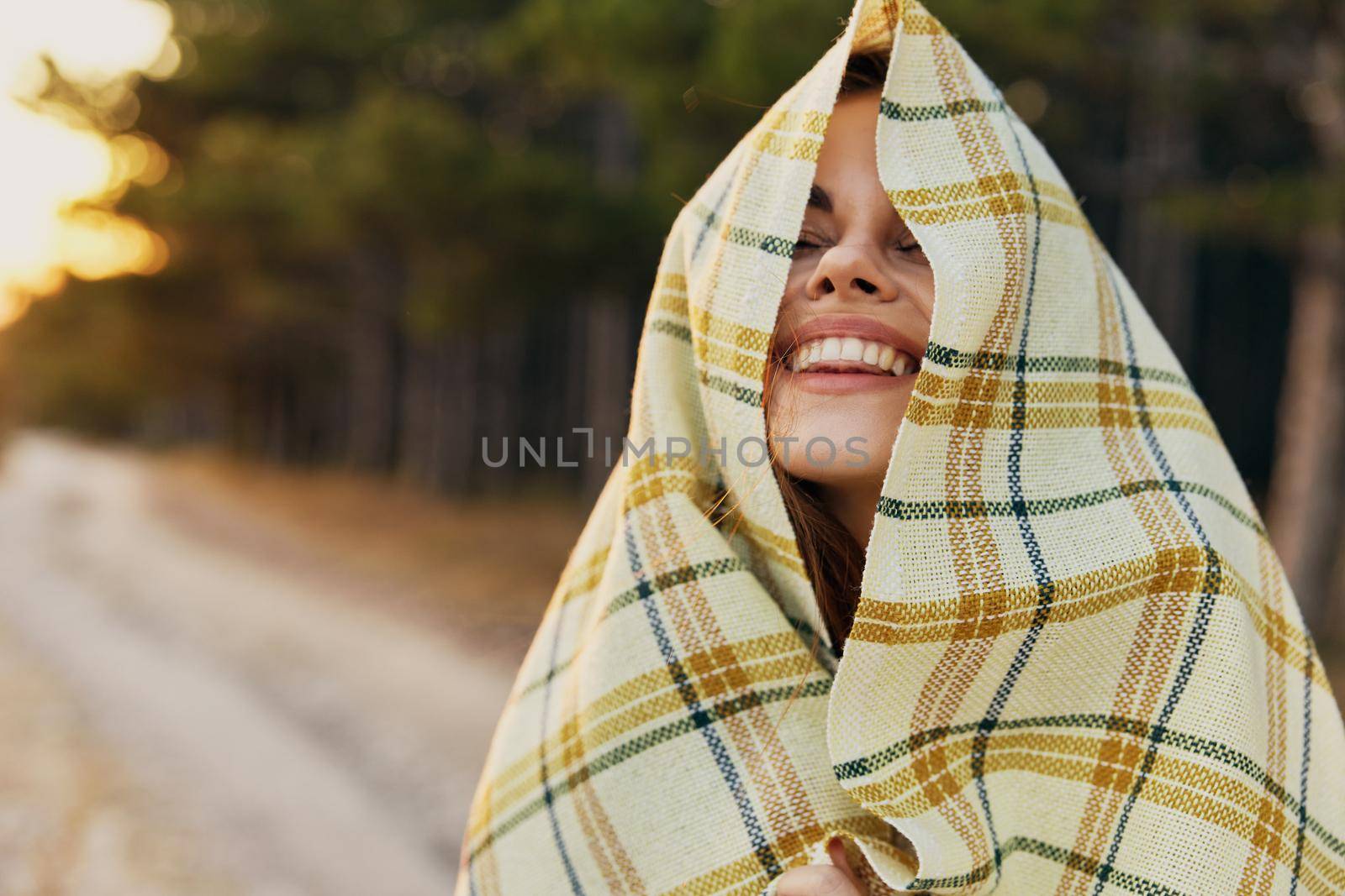 Happy woman hiding behind a blanket in nature near the coniferous forest by SHOTPRIME