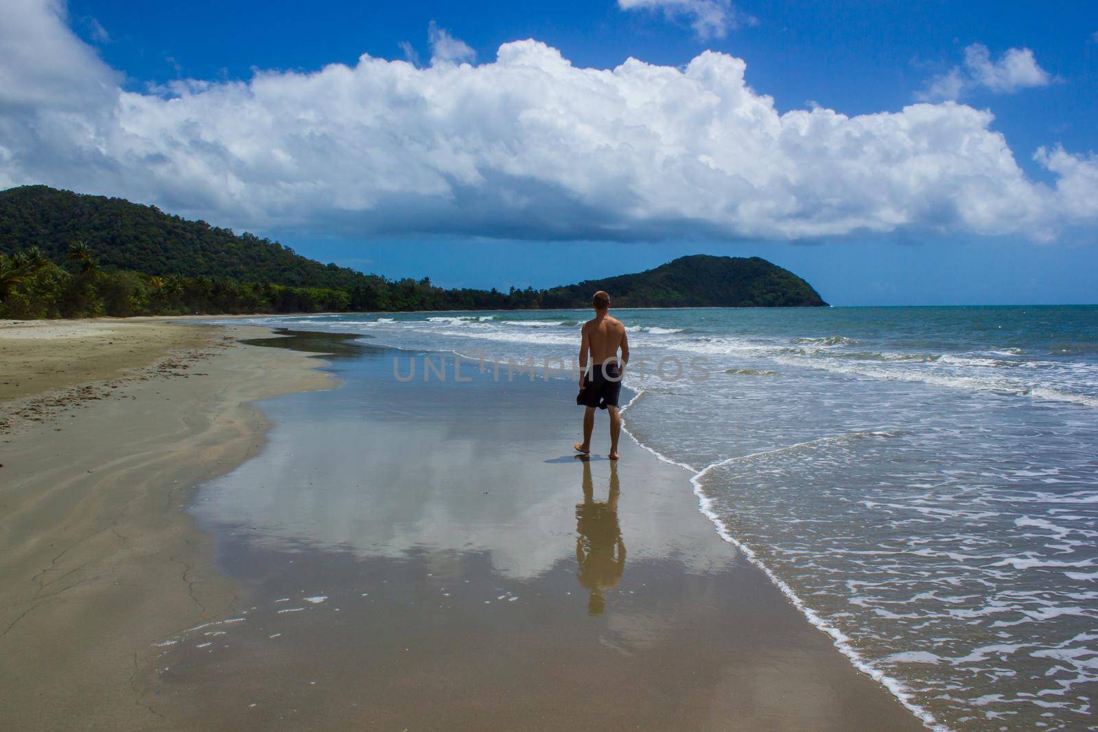 young man walking on the beach in Cape Tribulation in Daintree National Park in the far tropical north of Queensland, Australia by bettercallcurry