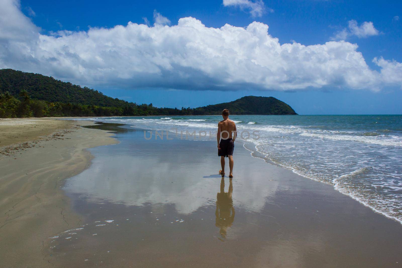 young man walking on the beach in Cape Tribulation in Daintree National Park in the far tropical north of Queensland, Australia by bettercallcurry