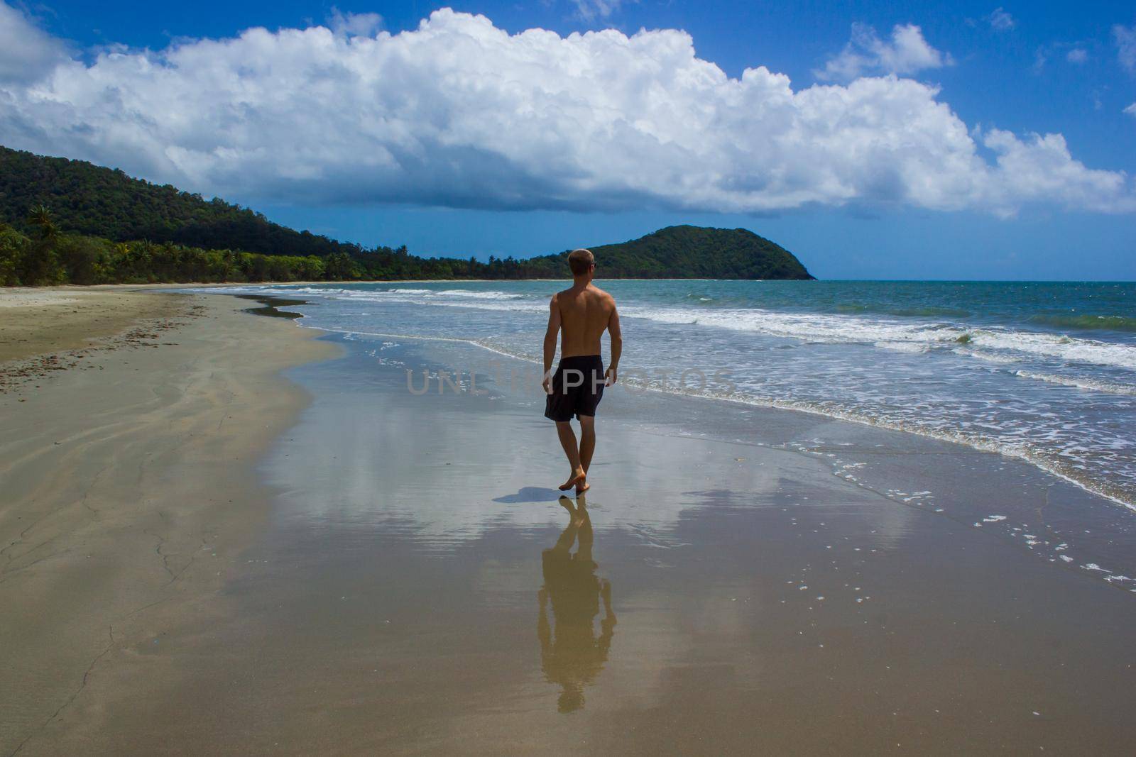 young man walking on the beach in Cape Tribulation in Daintree National Park in the far tropical north of Queensland, Australia by bettercallcurry