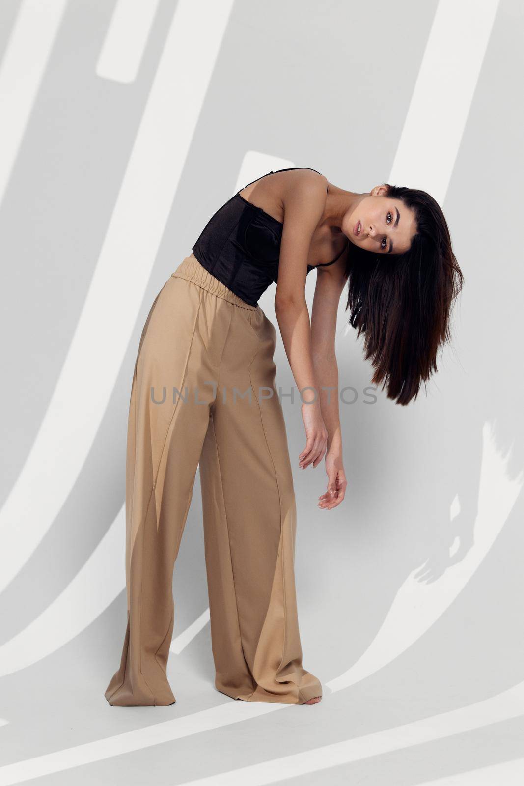 Emotional brunette in fashionable clothes bent over wavy hair by SHOTPRIME