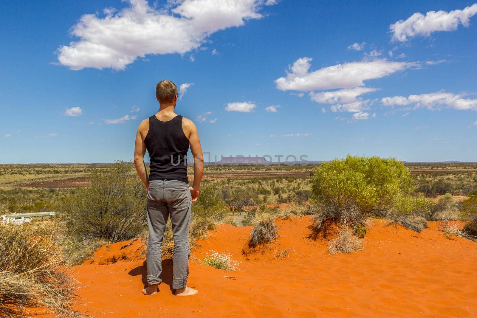 young man enyoing view of Mount Conner one of the spectacular landscape of Australian outback, Northern Territory, Australia. by bettercallcurry
