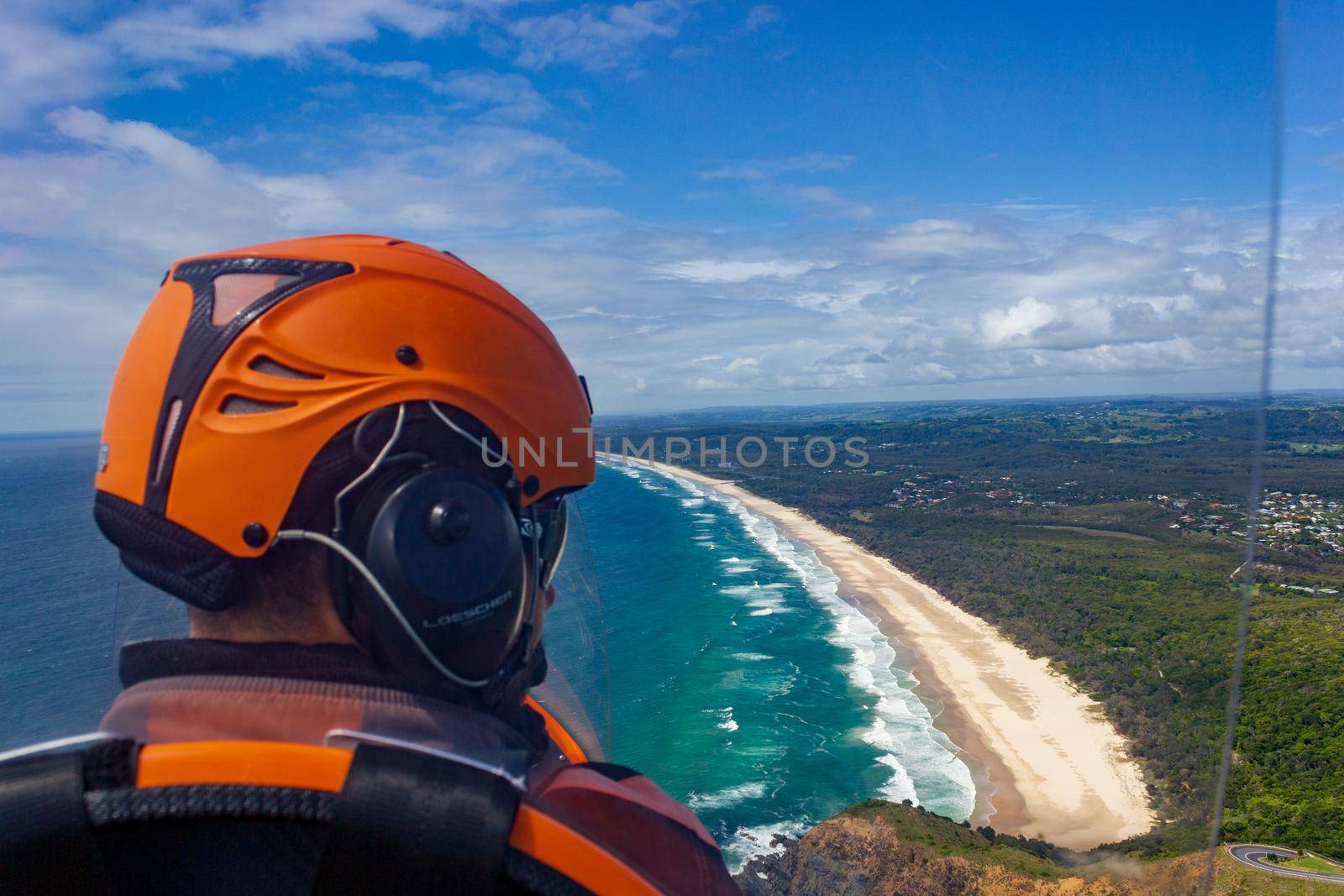 head of a pilot in a Gyrocopter with Wategoes Beach in the background, Byron Bay, Queensland, Australia.