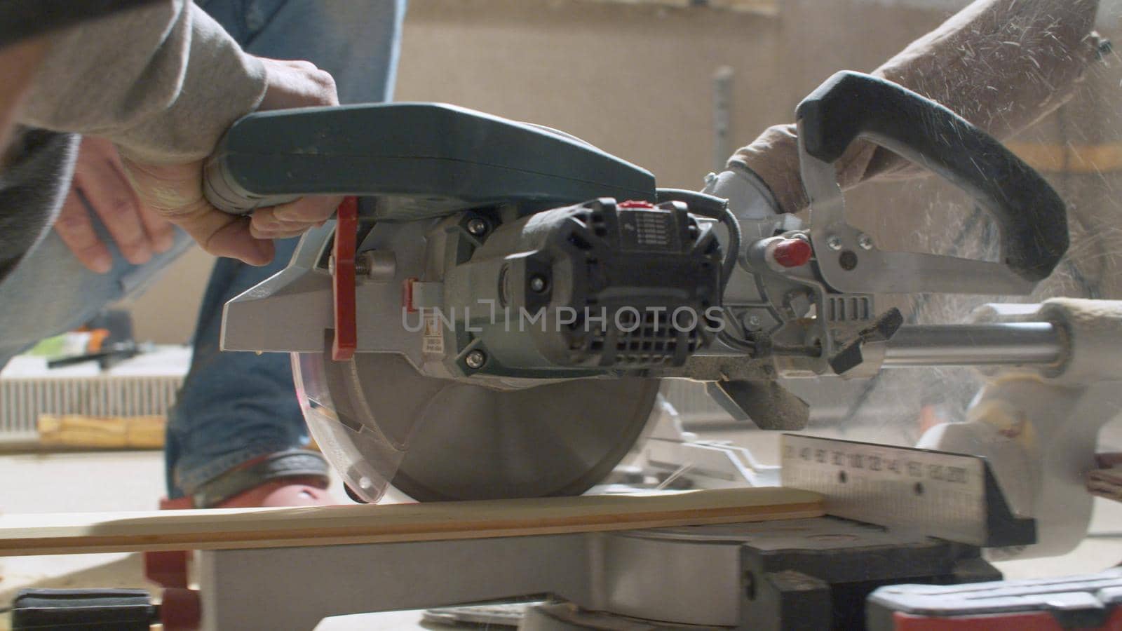 Close up carpenter cutting a plank with circular saw. Builder and woodworking