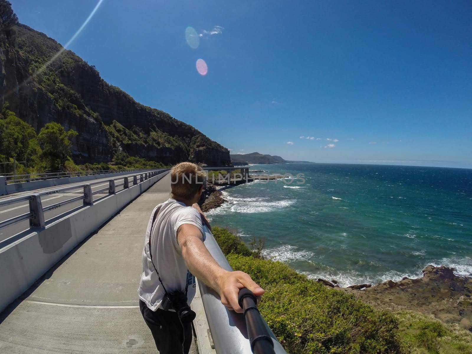 yung man making selfie at the Sea Cliff Bridge along the Grand Pacific Drive, Australia by bettercallcurry