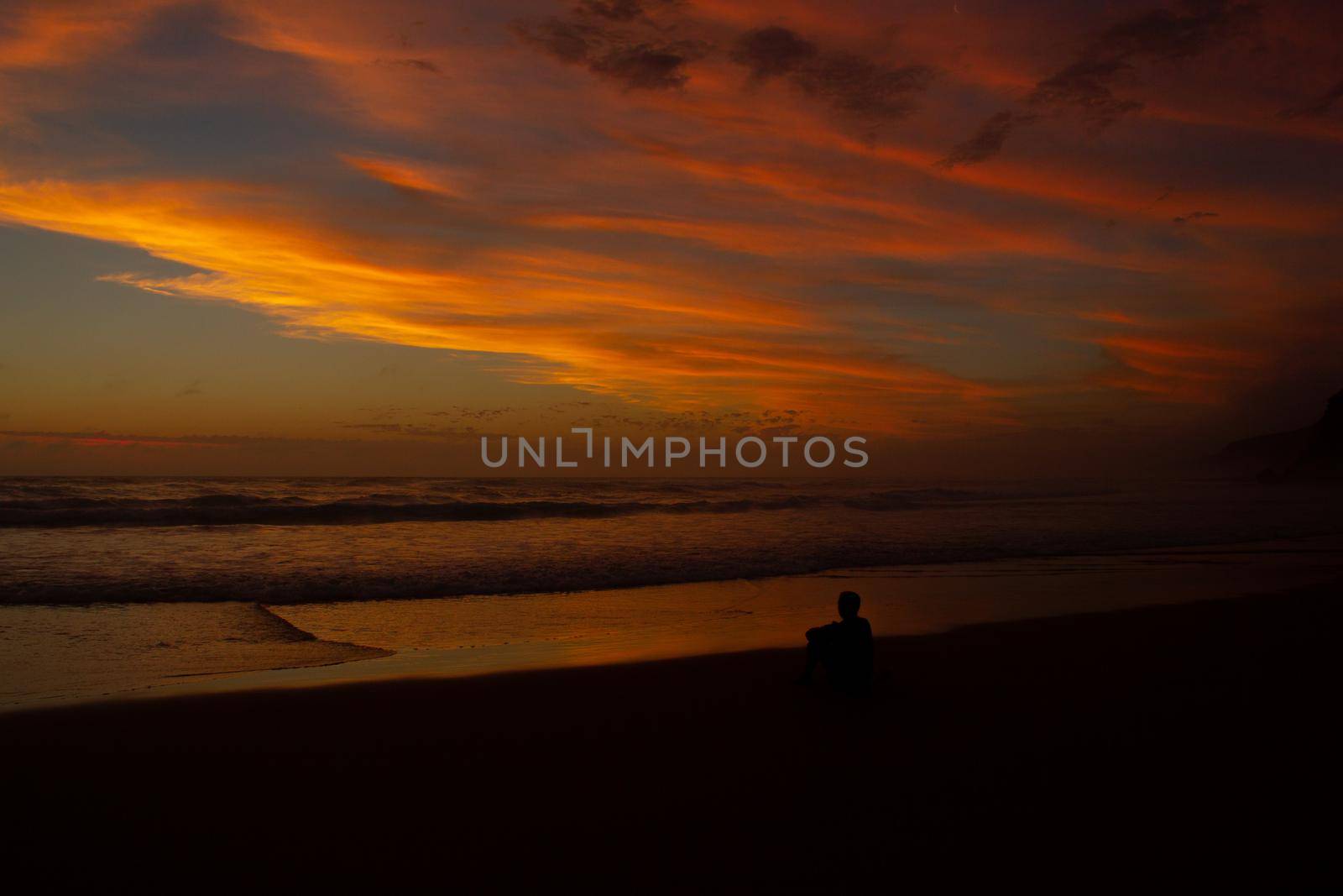 Young man sitting outdoors watching the sunset. Thinking and relaxing concept, Australia by bettercallcurry