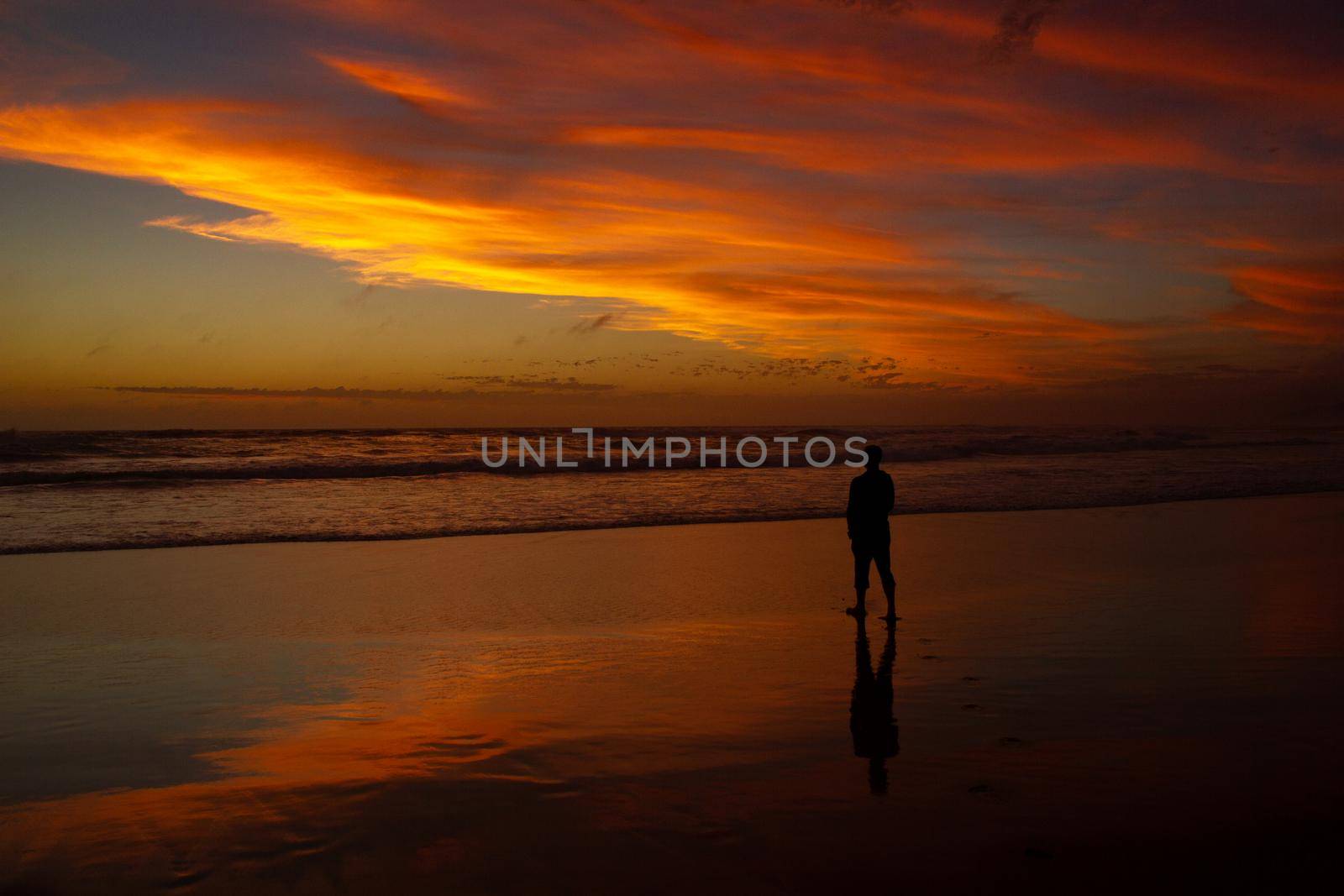Young man walking outdoors watching the sunset at a beach. Thinking and relaxing concept. by bettercallcurry