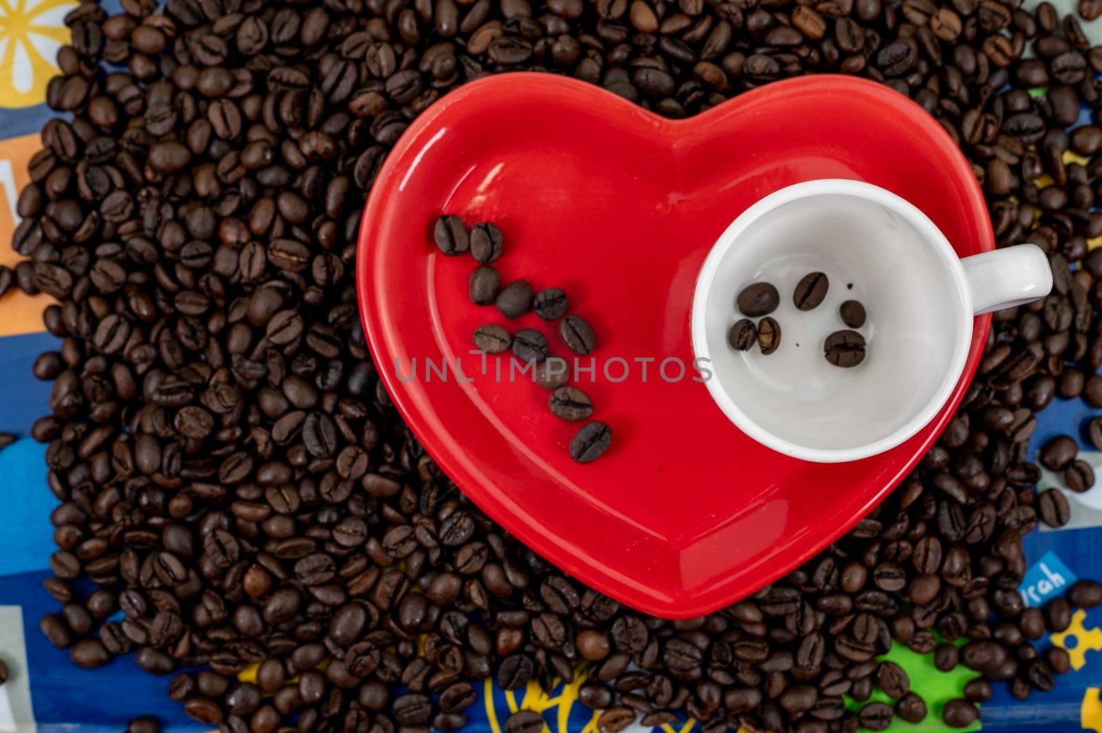 coffee grain composition in heart shape background with cup and saucer
