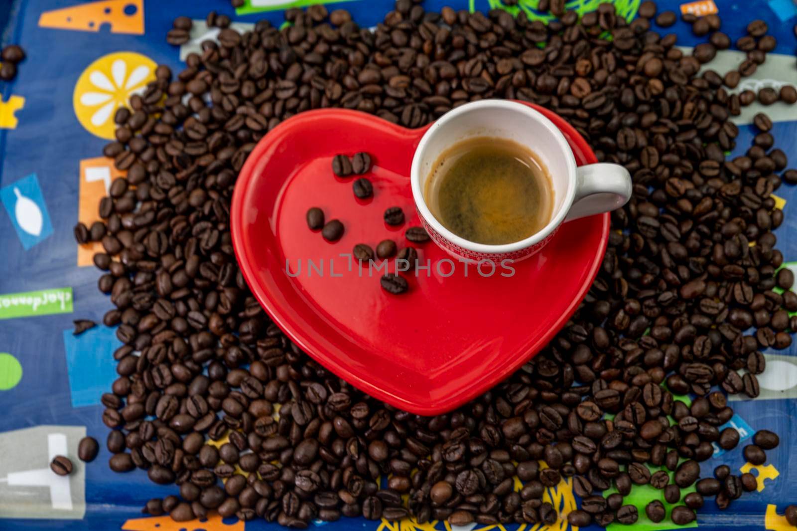 coffee grain composition in heart shape background with cup and saucer
