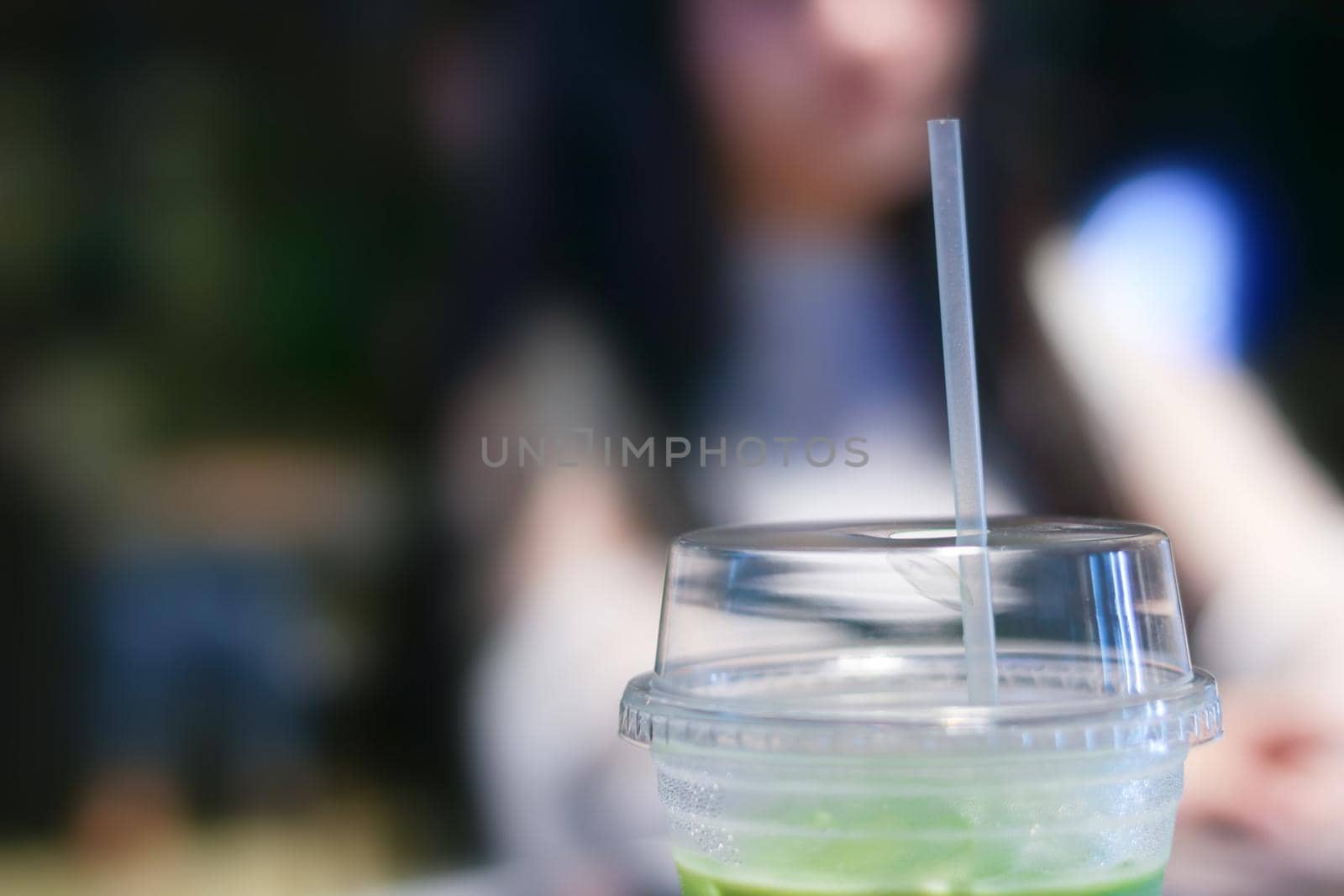 Iced matcha green tea latte on table with women working in store.