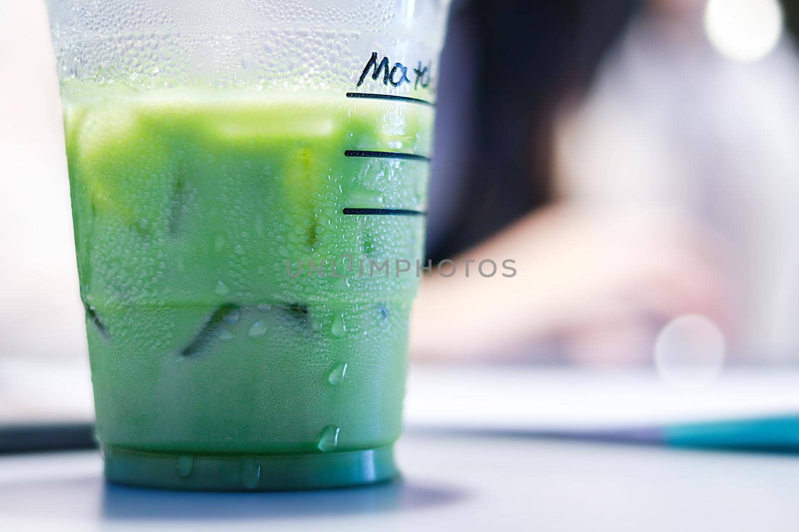 Iced matcha green tea latte on table with women working in store.