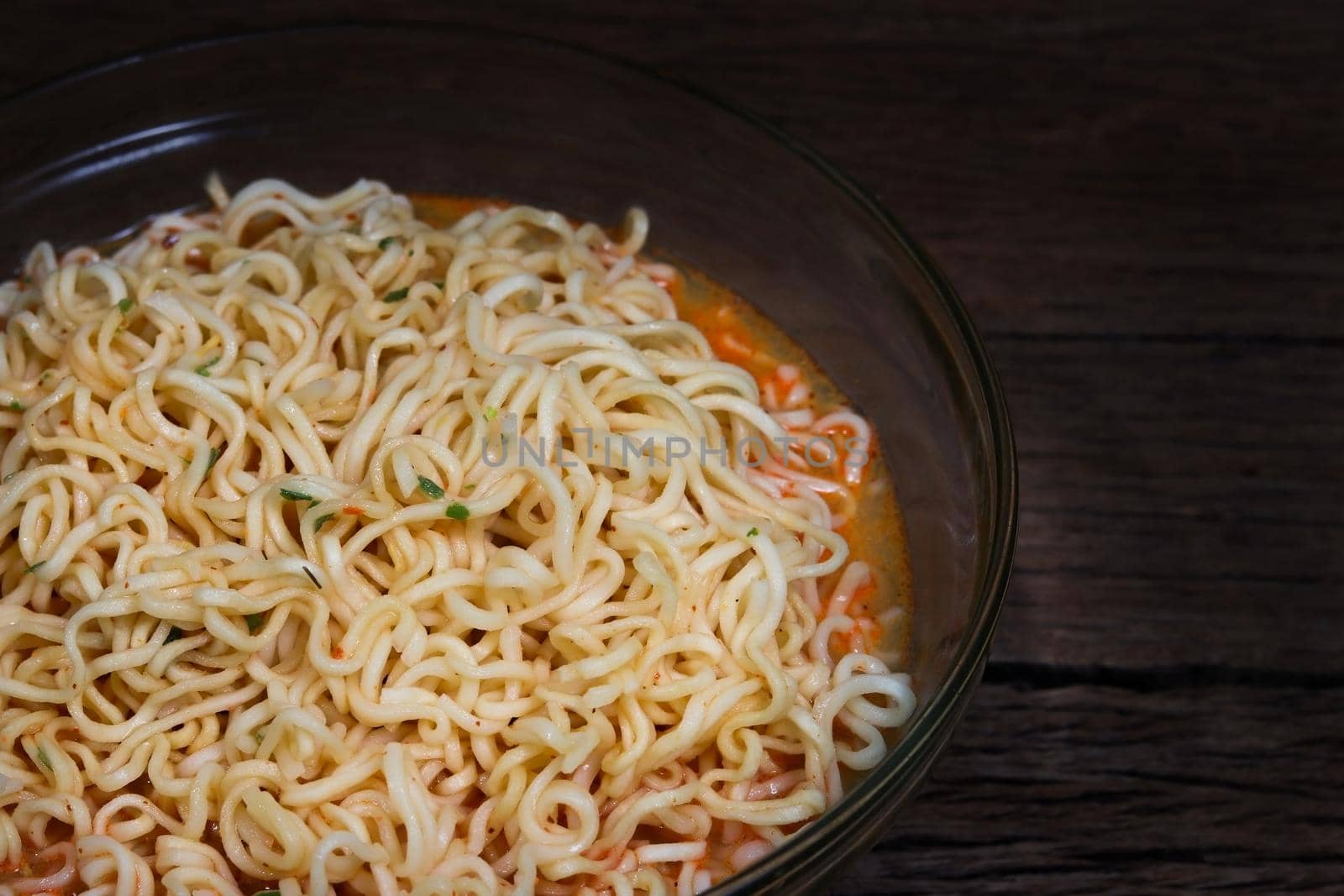 Instant noodles in bowl on wooden background.