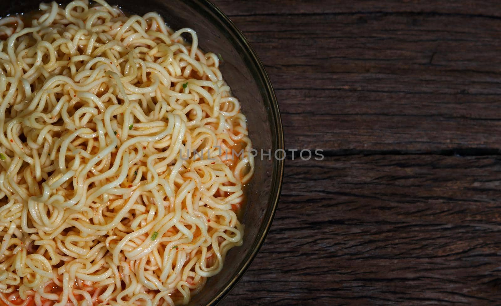 Instant noodles in bowl on wooden background.