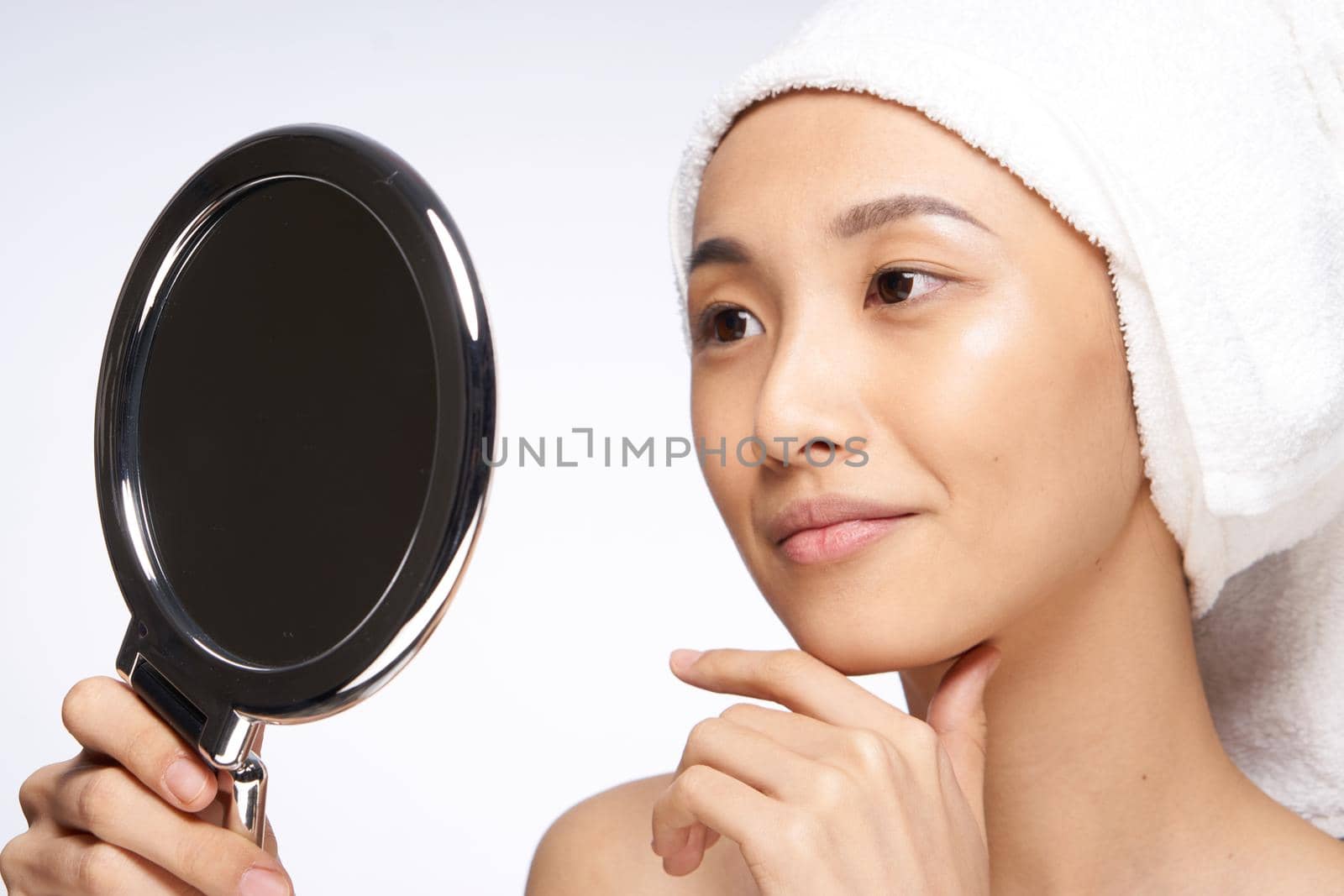 pretty asian woman looks in the mirror face close-up clean skin. High quality photo