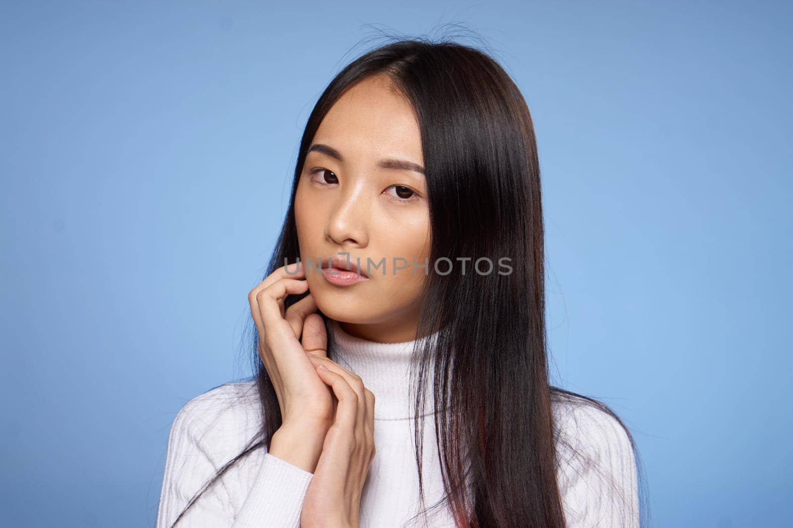 pretty woman with dark hair in white sweater gestures with her hands clean skin cosmetology by SHOTPRIME