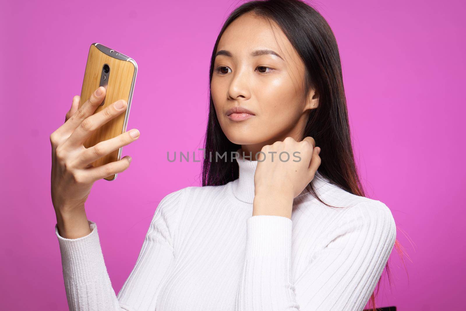 asian woman holding phone he communication technology internet pink background. High quality photo