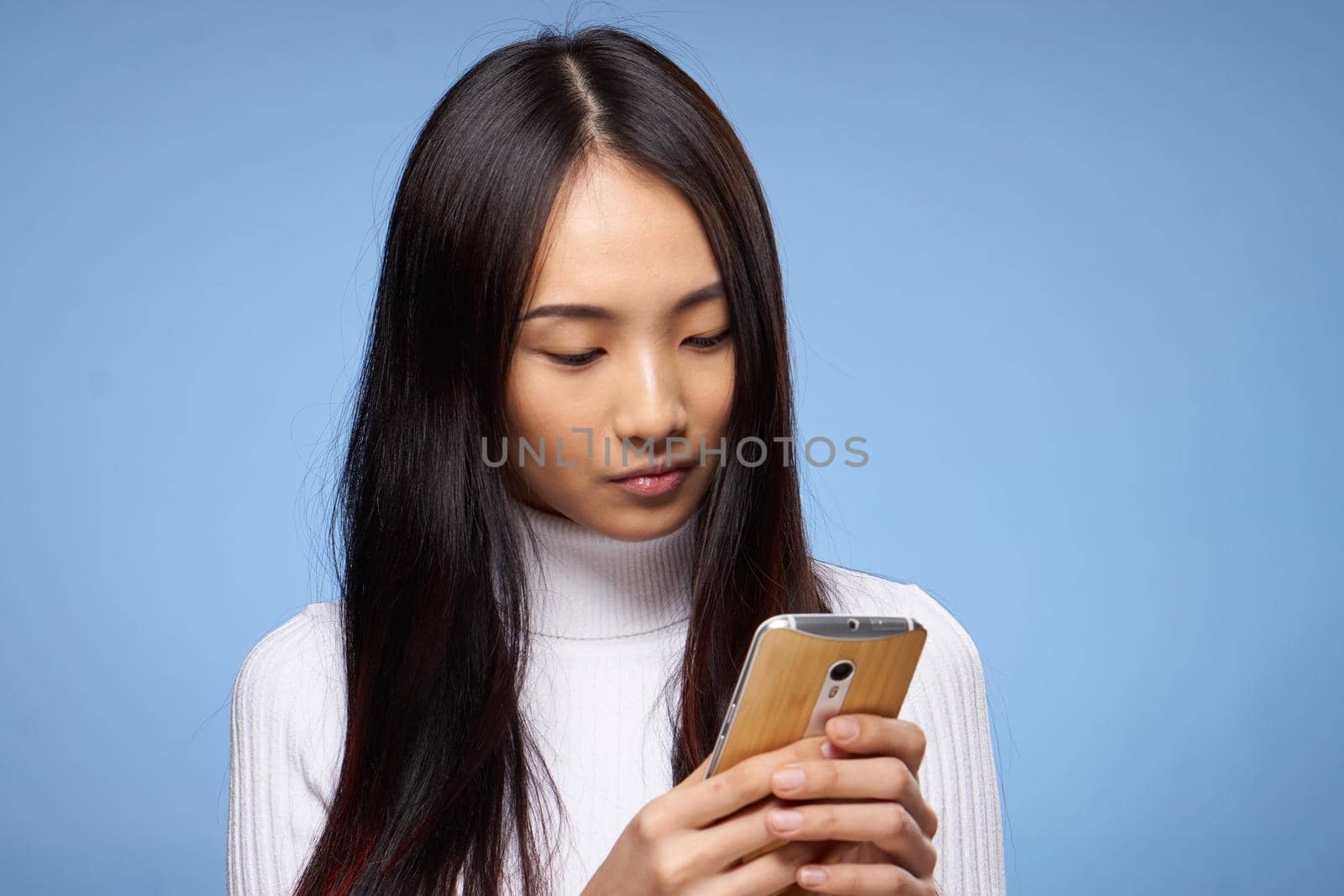 pretty brunette with phone in hand communication internet technology blue background. High quality photo