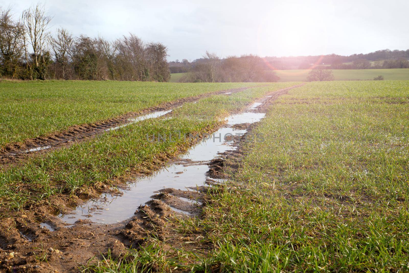 Muddy wet filed, countryside road, dirty road with water after heavy rain, spring time. Flood water in fields during sunny day. Global floods risk under climate change Suffolk UK