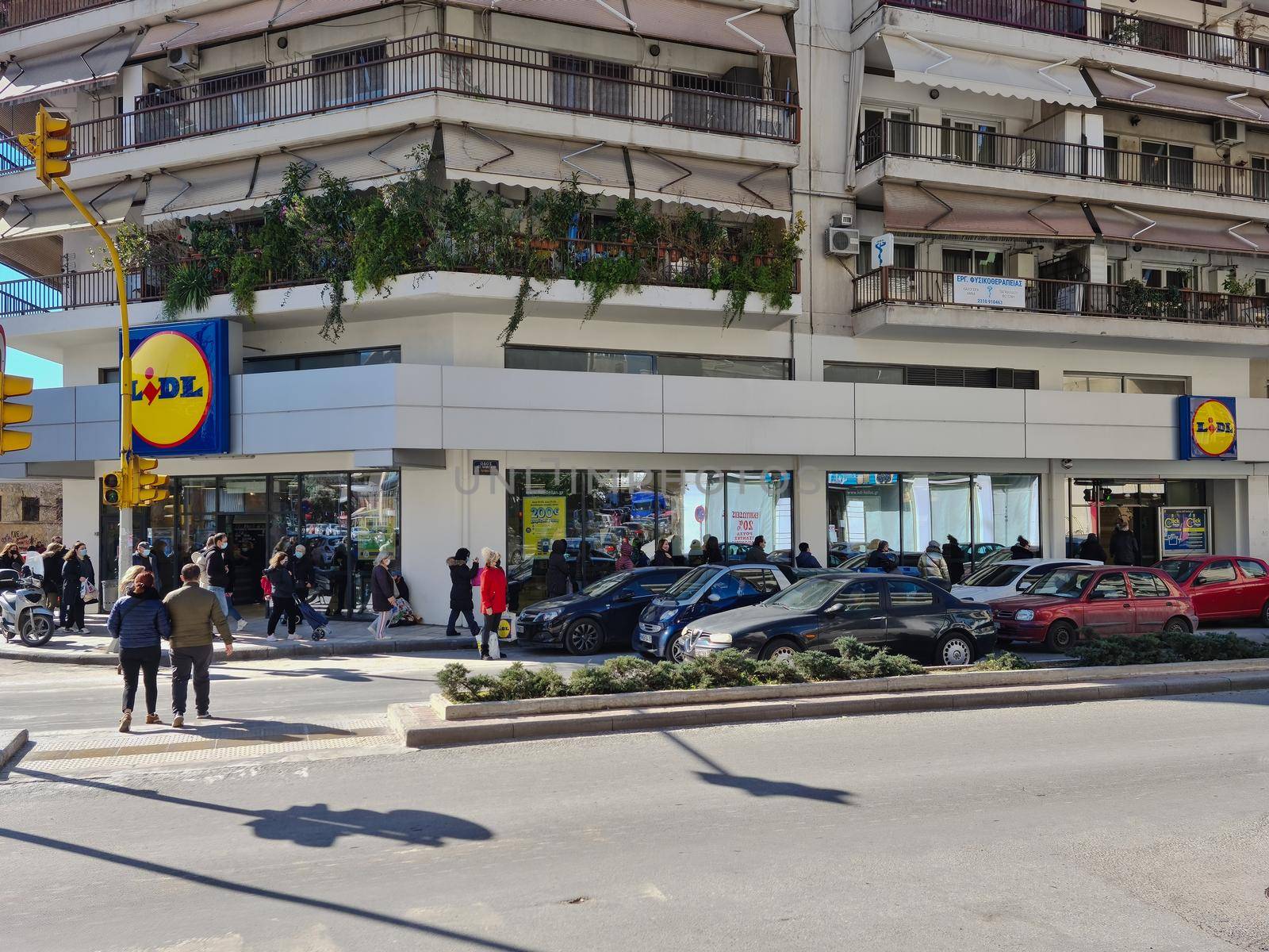 Large number of people with face protection wait in line to enter LIDL Stiftung German discount store.