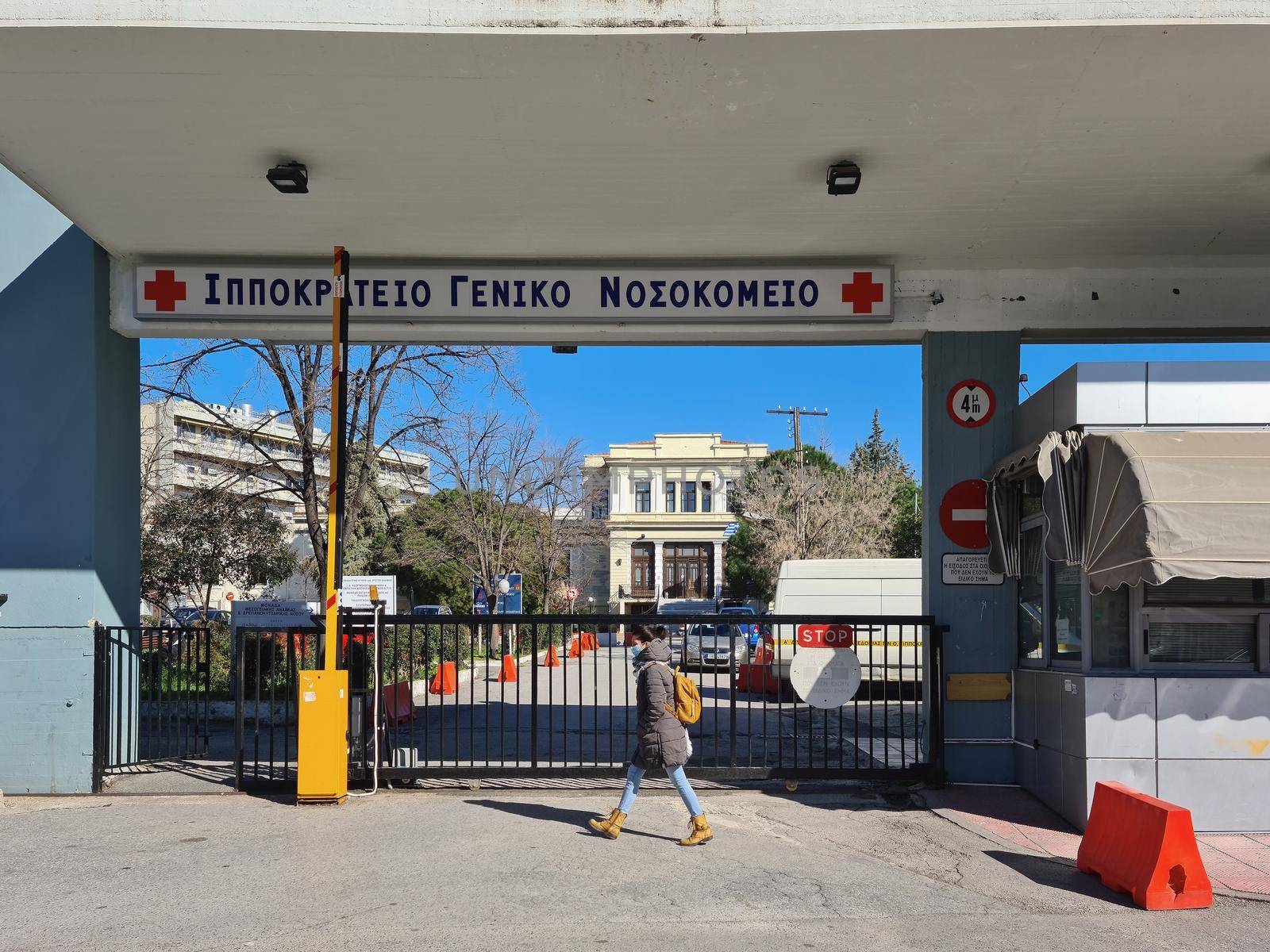 Day view of south gate facade of Hellenic public clinic with logo and red cross.