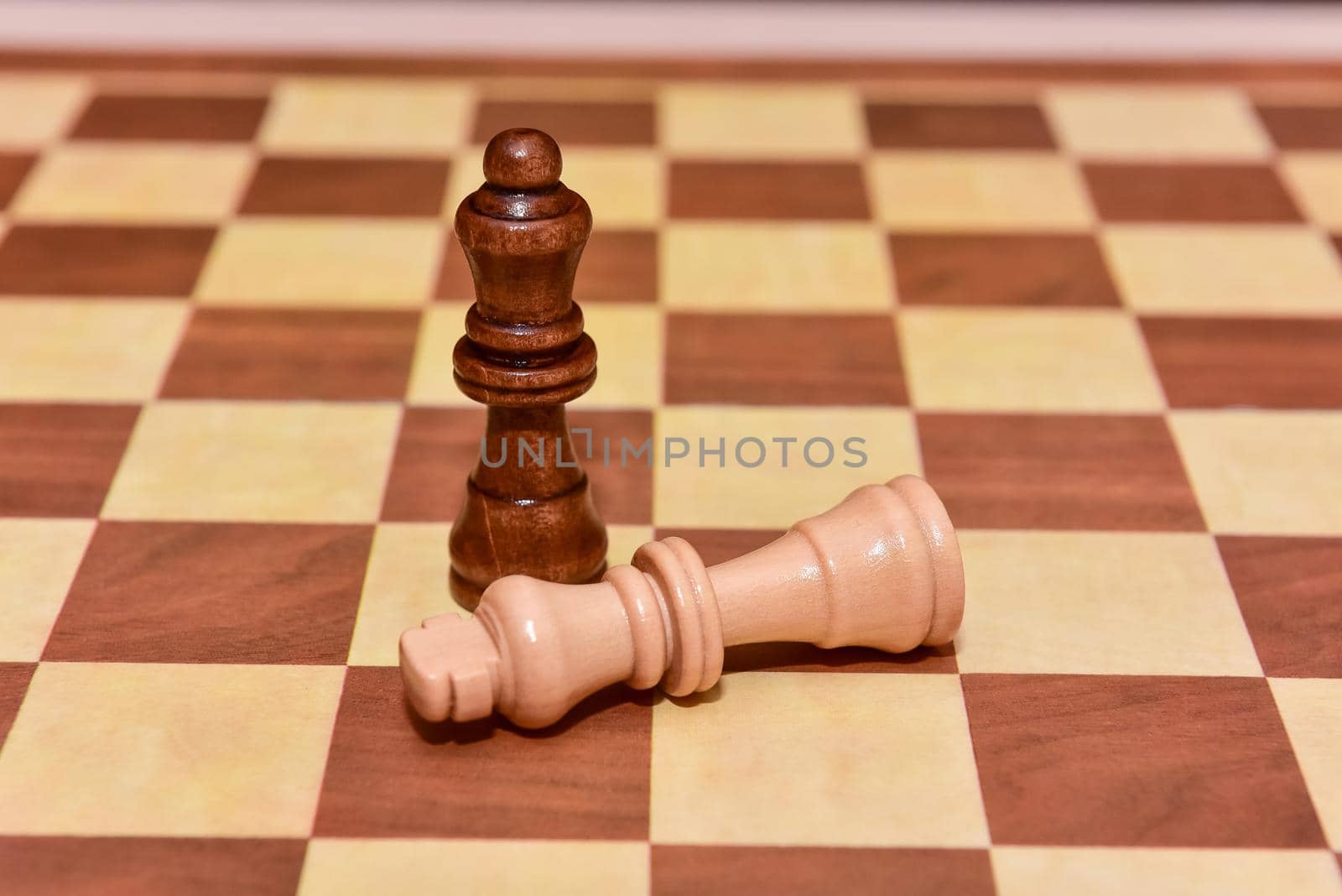 wood chess pieces on board game. brown vintage background. checkmate. the king is defeated by the queen.