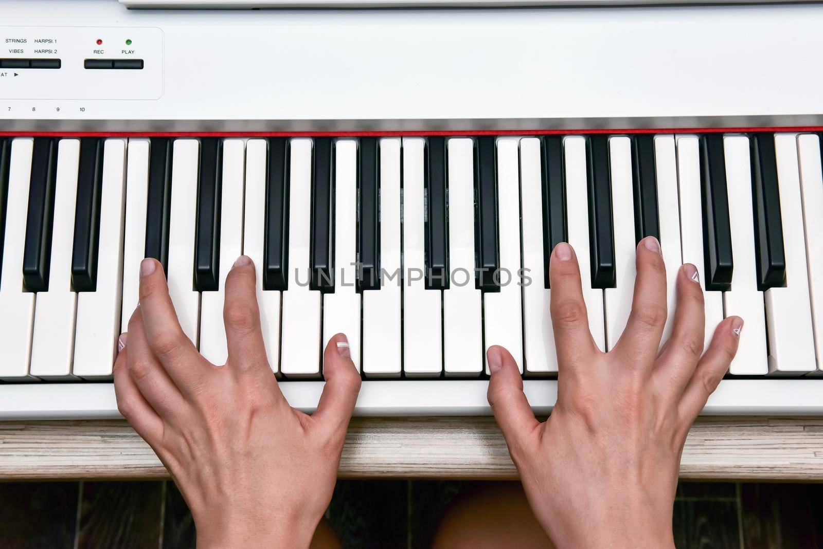 Woman's hands playing electronic digital piano at home. The woman is professional pianist arranging music using piano electronic keyboards. Musician practicing keyboard composing music.