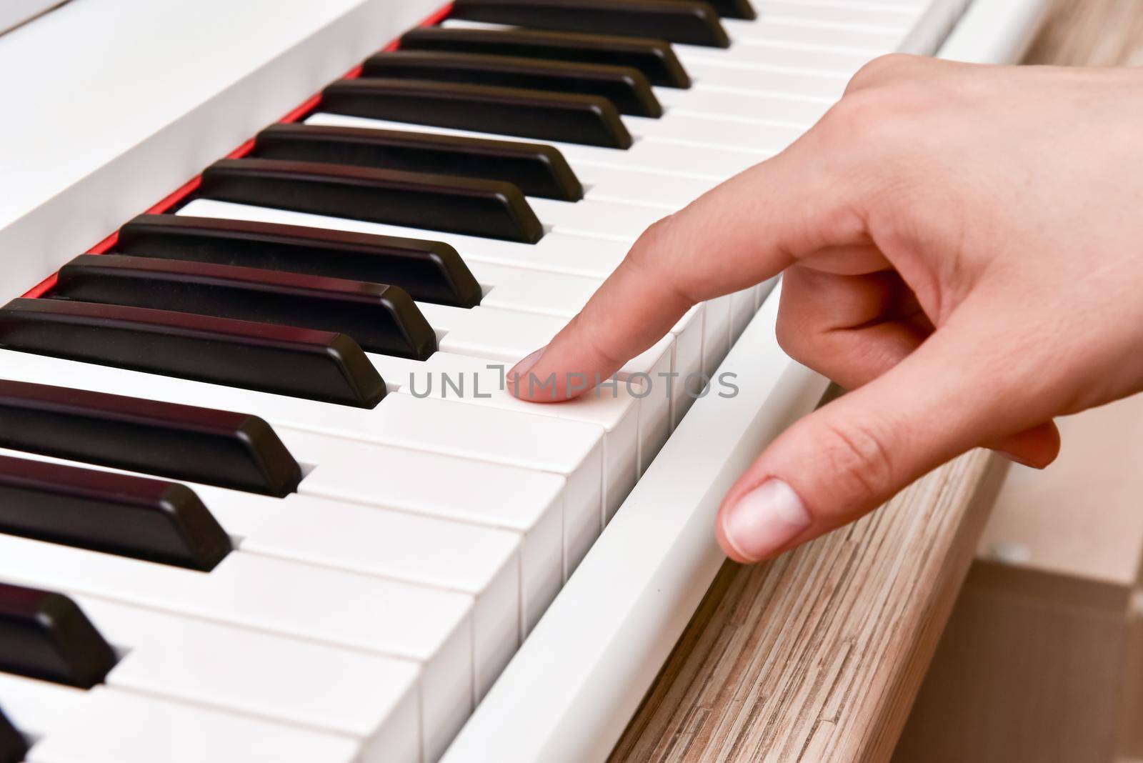 Woman's hands playing electronic digital piano at home. The woman is professional pianist arranging music using piano electronic keyboards. Musician practicing keyboard composing music.